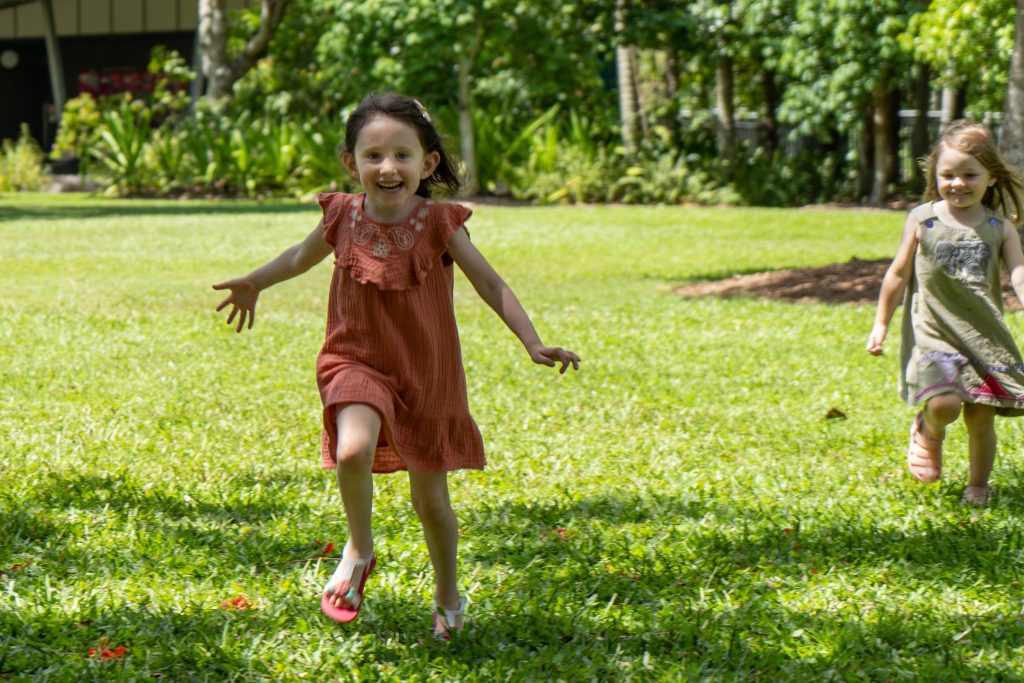 Two kids running towards the camera during an outdoor photo shoot